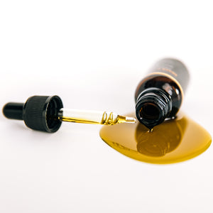 Rehab CBD Serum bottle on its side with dropper and product spilling out to show reddish color and texture by THE WILDNESS